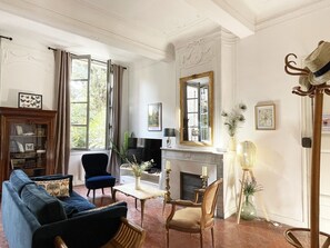 Un salon bien éclairé, doté d’une cheminée, d’un canapé bleu, d’une chaise en bois et d’un téléviseur.