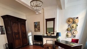 Een kamer met een bed, bureau, spiegel en een kroonluchter.