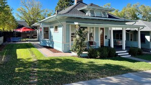 A light blue house with a porch, a chimney, and a mailbox.