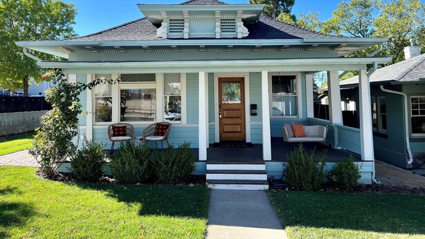 A two-story house with a porch, a front door, and a mailbox.
