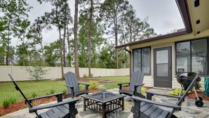 Une terrasse avec des fauteuils Adirondack, un foyer et un espace barbecue.