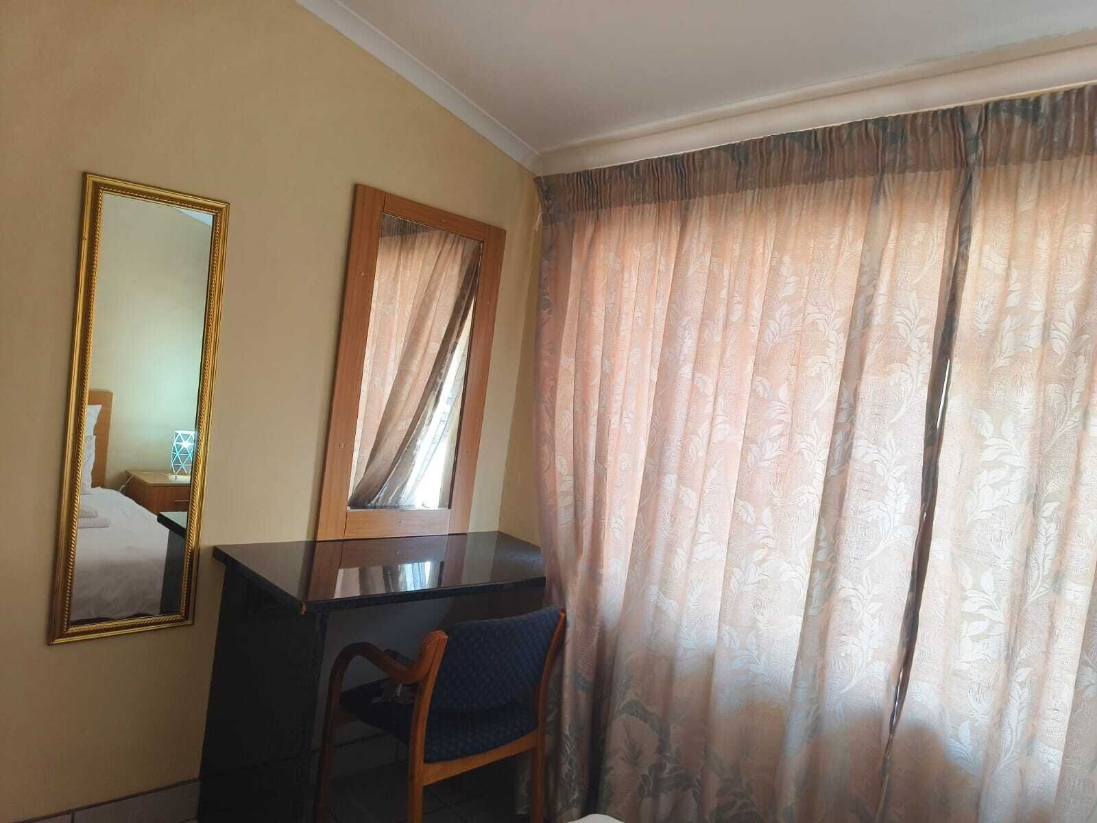 Een kamer met een bureau, stoel en een grote spiegel.