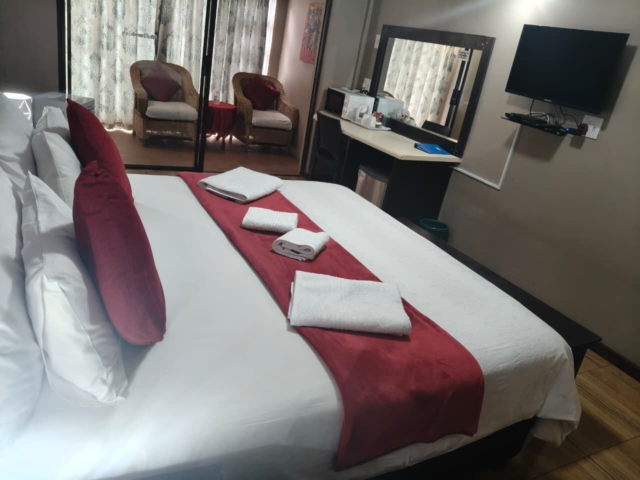 Une chambre d’hôtel avec un lit, une télévision, un bureau et une chaise.