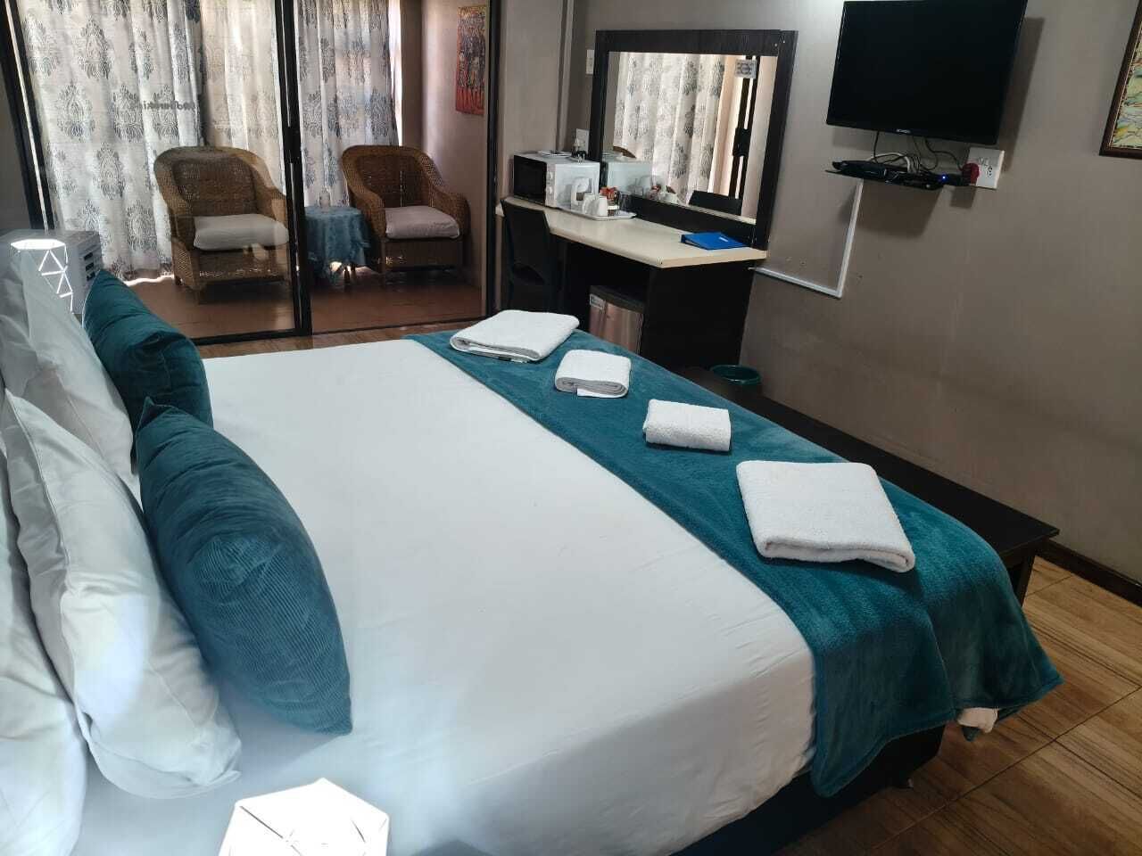 A hotel room with a bed, a desk, a television, and a chair.