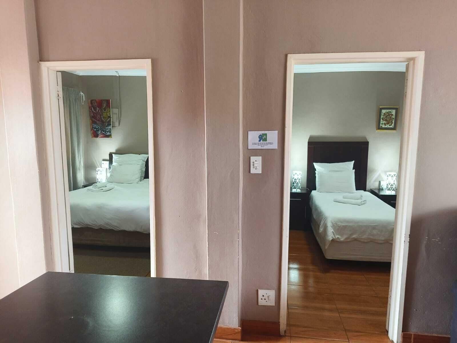 Une chambre d’hôtel avec deux lits, une petite table et un miroir.
