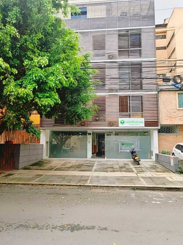 A modern building with a business center sign, large windows, and a tree in front. - HOTEL KING VERSALLES (Cali)