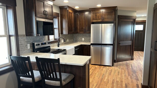 Una cocina moderna con armarios de madera oscura, electrodomésticos de acero inoxidable y una isla grande con dos sillas.