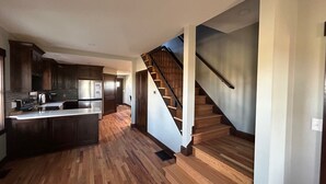 Una cocina moderna con suelo de madera, una isla central y una escalera que sube a otro nivel.