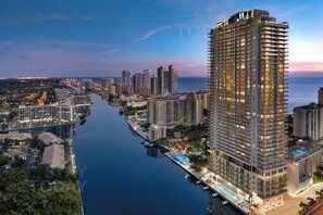 A high-rise hotel with multiple floors, a swimming pool, and a waterfront view.