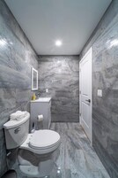 A bathroom with a toilet, sink, and mirror.