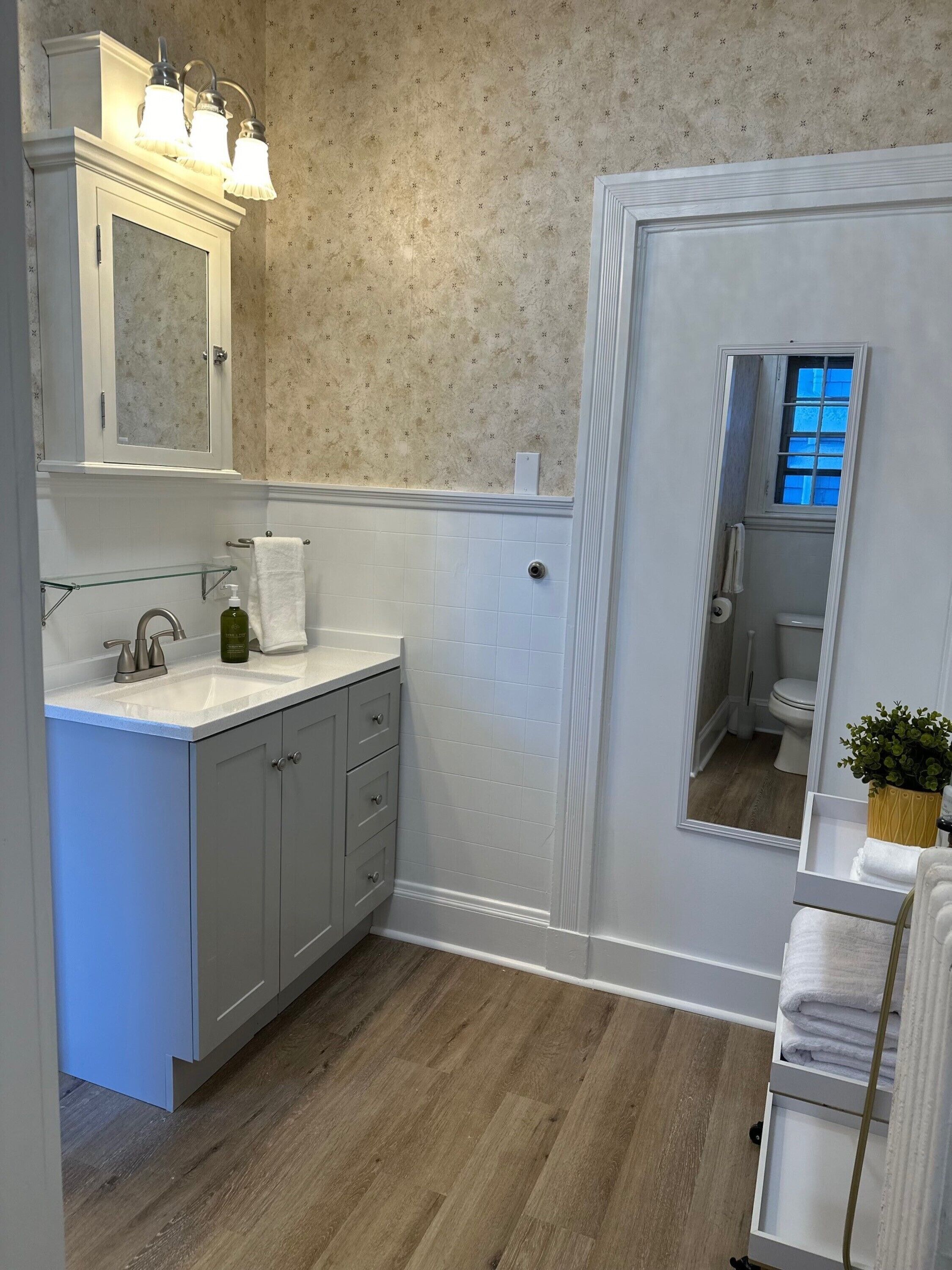 A bathroom with a vanity, mirror, and a small window.
