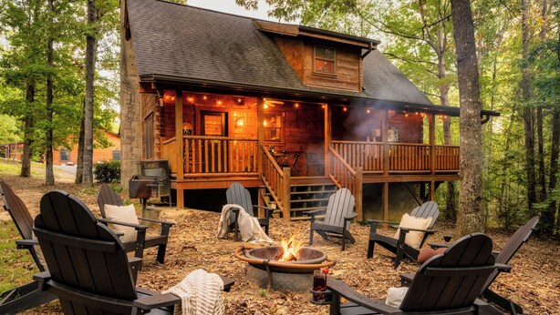 A cabin with a deck, outdoor seating, and a fire pit.