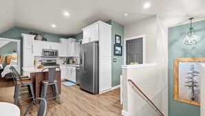 Una cocina moderna con armarios blancos, electrodomésticos de acero inoxidable y una zona de comedor de madera.