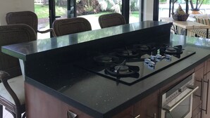 Cozinha moderna com ilha central, eletrodomésticos de aço inoxidável e amplas janelas com vista para um jardim exuberante.