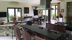 Cozinha moderna com ilha central, área de jantar e televisão fixada na parede.