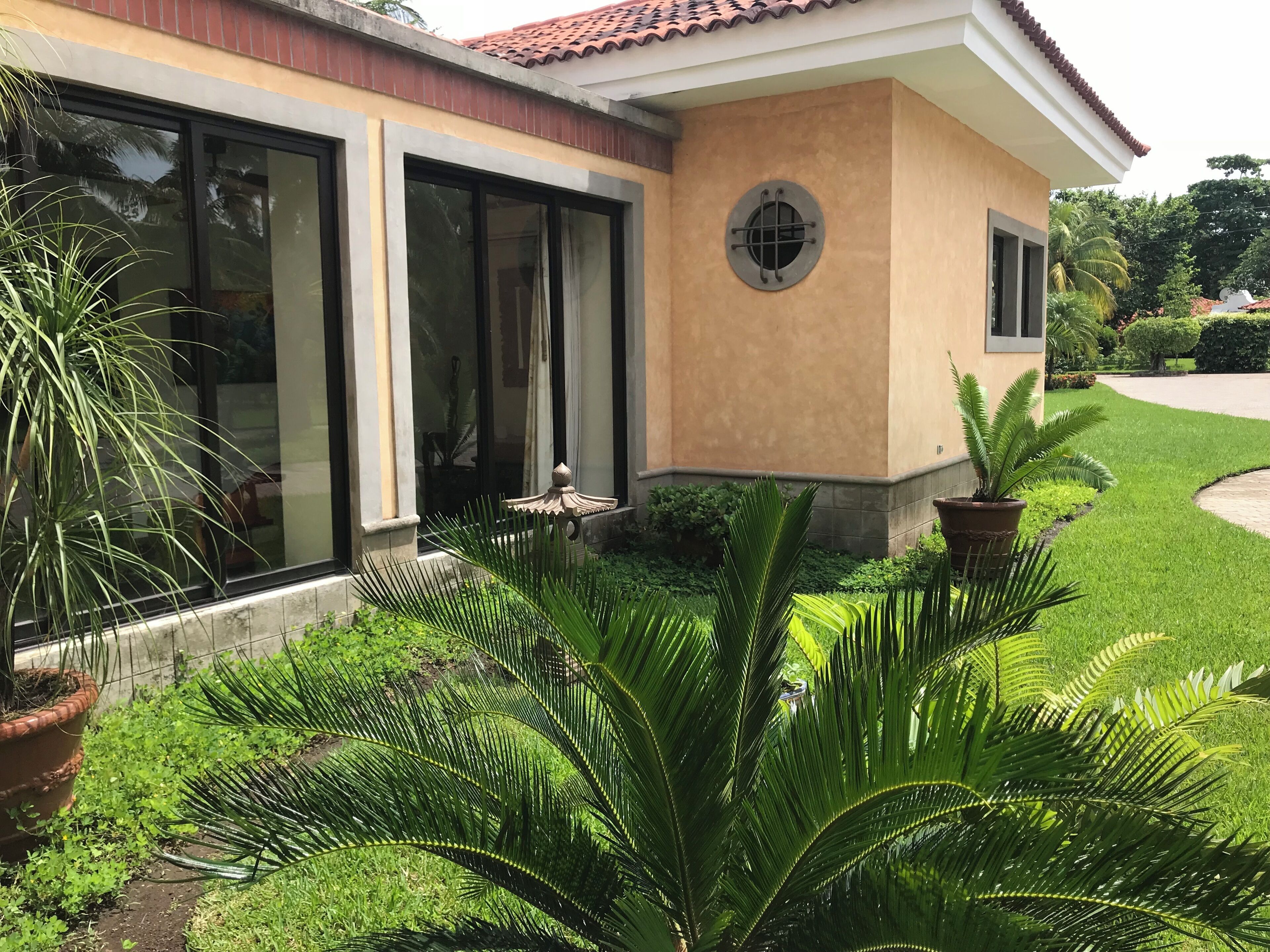 A house with large glass doors, a small porch, and a well-maintained garden with various plants.