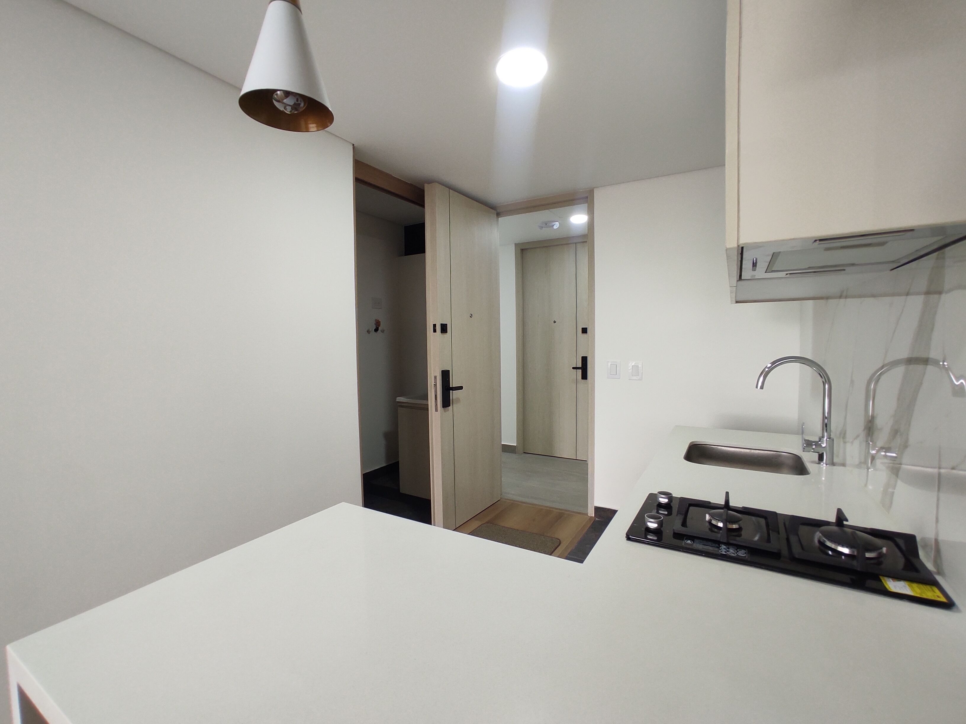 A compact kitchen with a gas stove, a sink, and a ceiling light.
