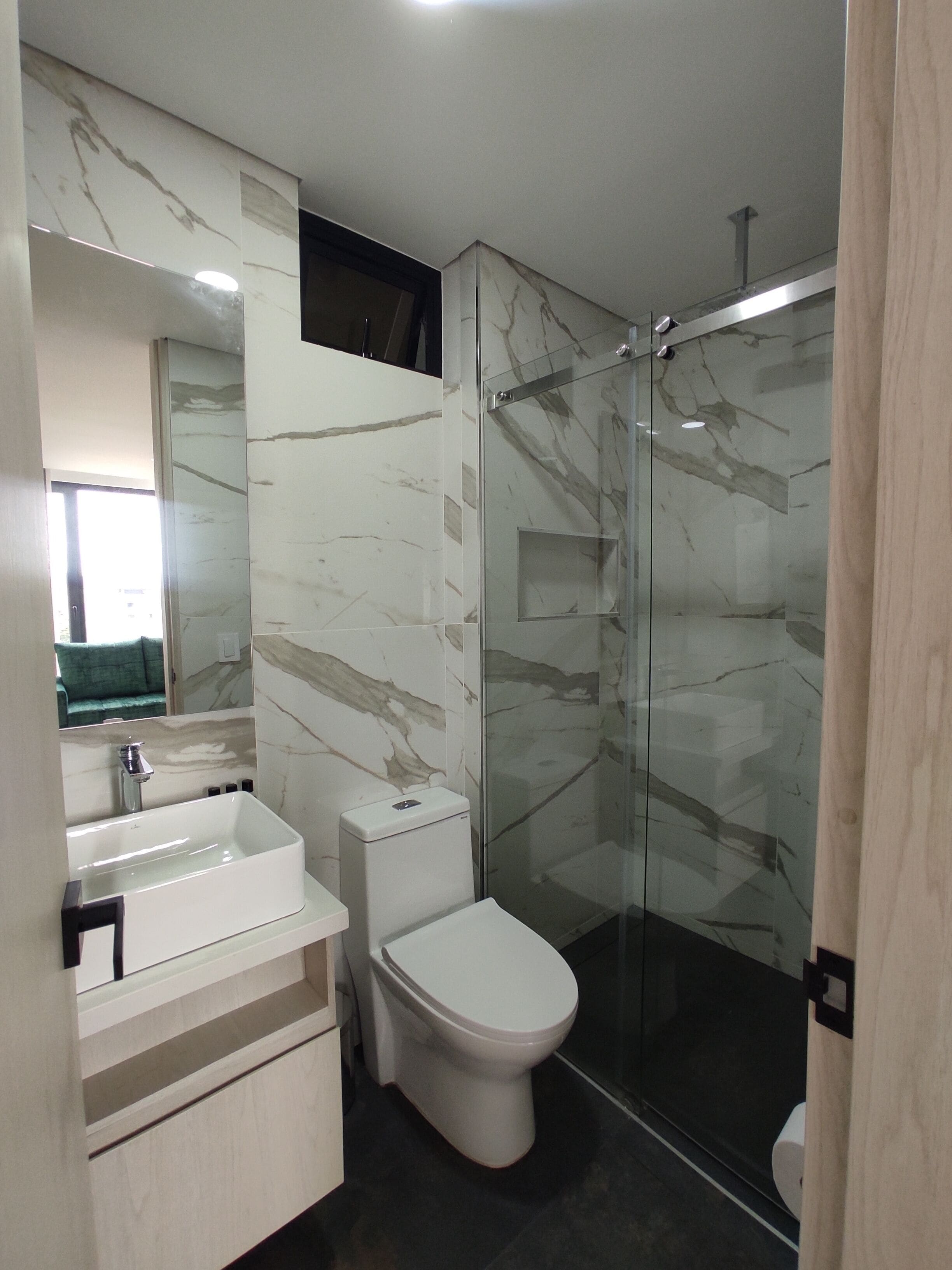A modern bathroom with a glass-enclosed shower, a white sink, and a toilet.