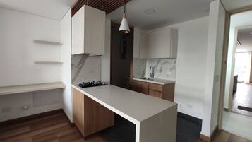 A modern kitchen with a central island, wooden cabinets, and a marble backsplash.