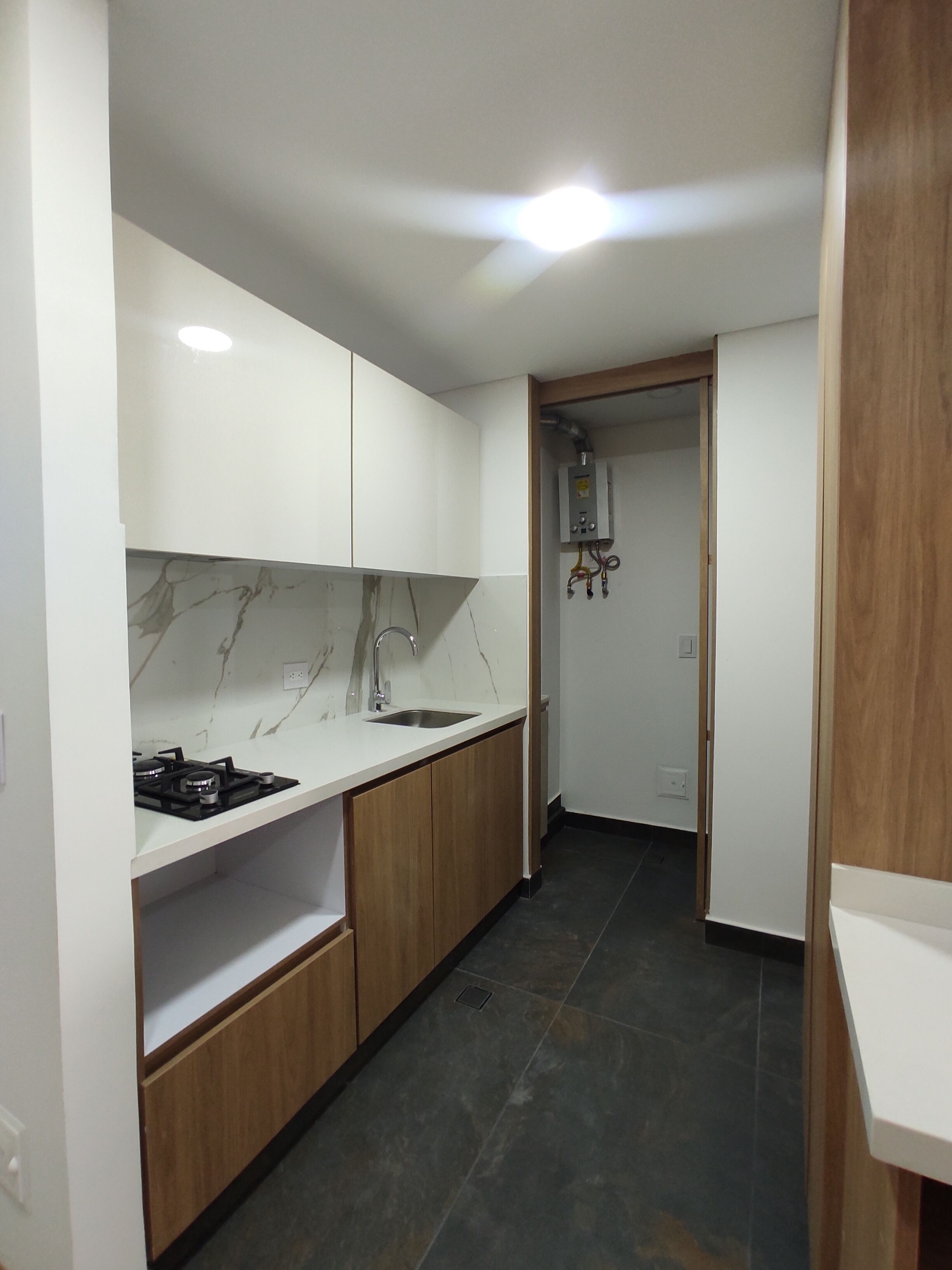 A compact kitchen with white cabinets, a marble backsplash, and a black stove.