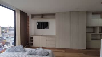 Une chambre à coucher comprenant un lit, un téléviseur fixé au mur et des rangements intégrés.