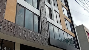 A modern building with a patterned facade, large windows, and a closed garage door. - Modelia Living & Parking (Bogotá)