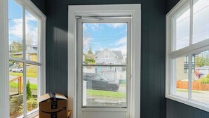 Une pièce d’angle avec un mur foncé, une porte blanche et une vue sur une rue résidentielle.