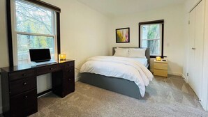 Une chambre à coucher avec un lit, un bureau et deux fenêtres.