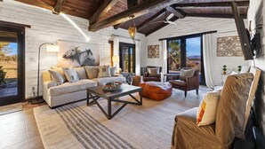 Un salon spacieux avec un grand canapé, une table basse et une cheminée. Une grande fenêtre offre une vue sur l’extérieur.