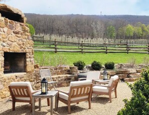 Una chimenea de piedra con asientos exteriores y vista a un pastizal cercado.