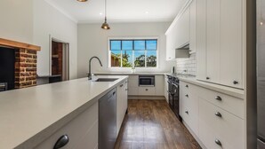 A modern kitchen with a large island, white cabinetry, and a view through a window. - Springfields Homestead - Rapaura Holiday Home (Blenheim)