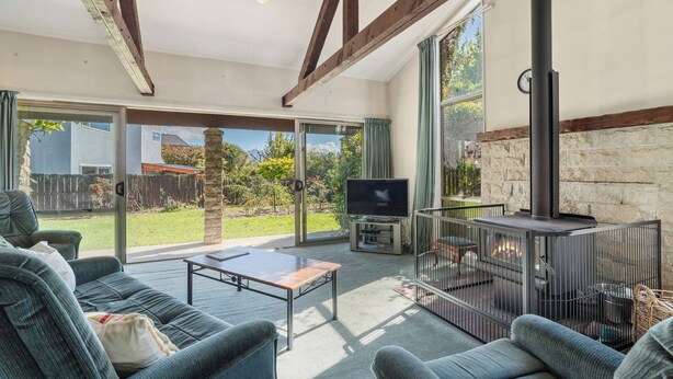 A spacious living area with a fireplace, a television, and comfortable seating. - Sunlit Solace - Wanaka Holiday Home (Wanaka)