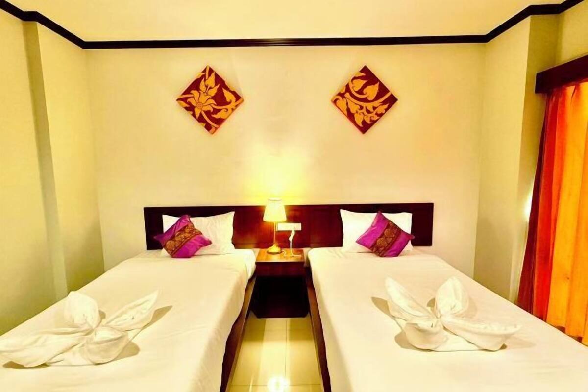 A hotel room with two beds, a nightstand, and decorative wall art.