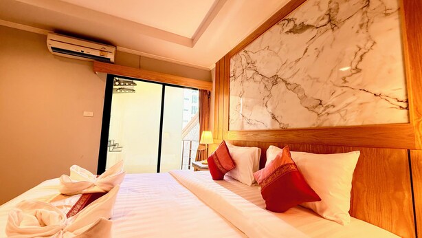 Een hotelkamer met een bed, kussens, een marmeren wand en een airconditioningsysteem.
