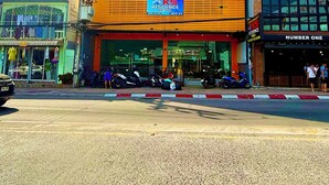 Een meerlaags gebouw met een bordje voor 'KS Residence Patong' en een traditionele constructie in de buurt.