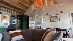 A cozy living area with a brown sofa, a dining table, and a staircase leading to an upper level. - Stunning Views & Heated Cowboy Pool 5 min to River (Canyon Lake)