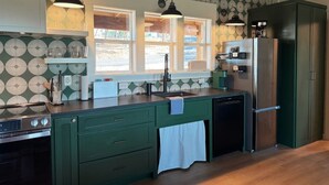 A kitchen with green cabinets, a stainless steel refrigerator, and a window with a view of the outdoors. - Stunning Views & Heated Cowboy Pool 5 min to River (Canyon Lake)