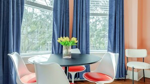 A dining area with a round table and four chairs, a vase with flowers, and blue curtains.