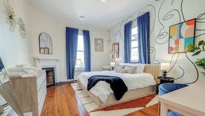 A modern bedroom with a large bed, a fireplace, and a view of the outdoors.