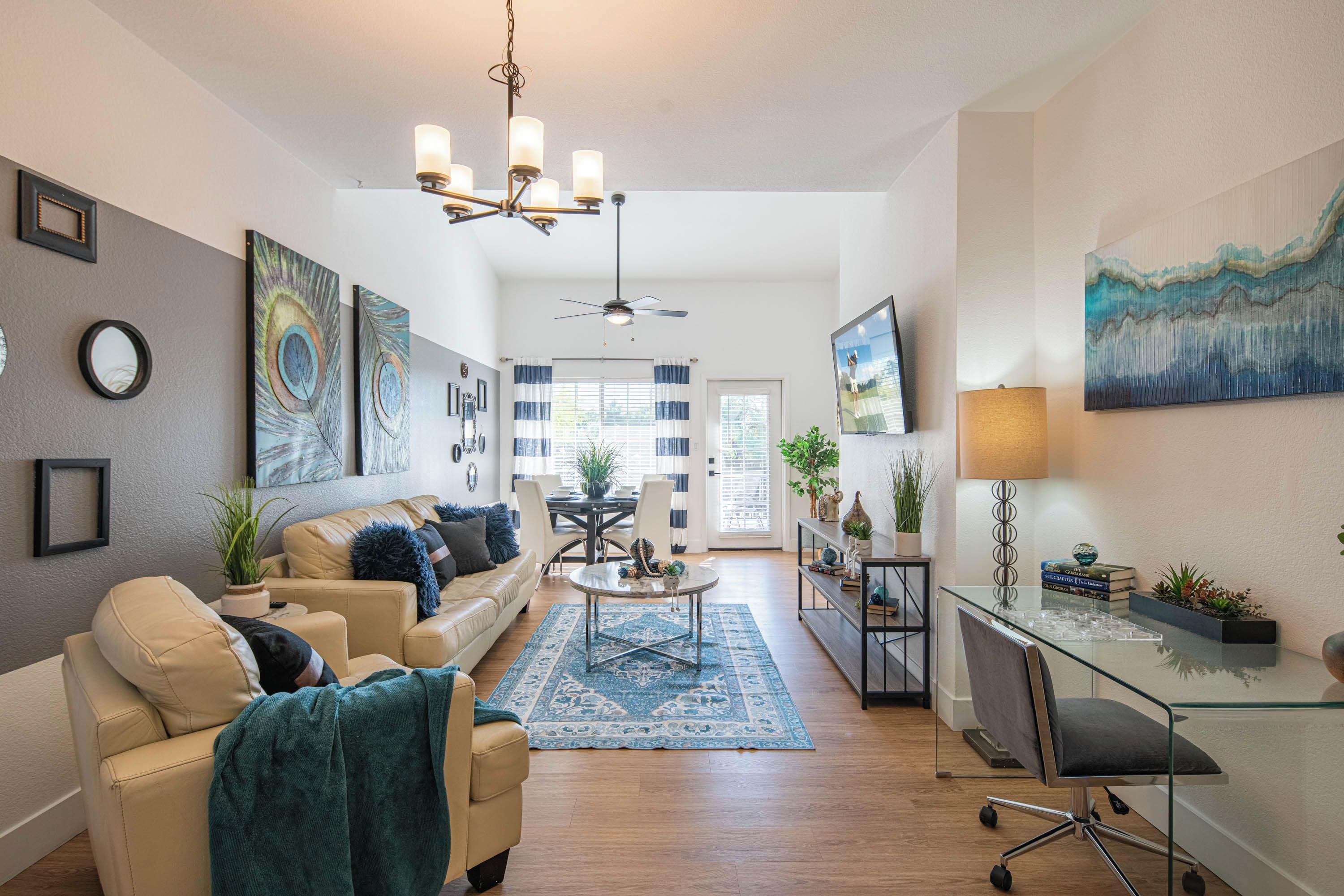 Un salon moderne avec un canapé beige, une table basse en verre et un coin repas comprenant une table et des chaises en verre.