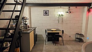 Et lille køkken med spiseplads, med et bord og stole, en vask og en stige.