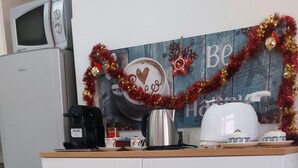 A kitchen with a microwave, coffee maker, and a decorative wall with holiday garlands. - Cozy Flat near Vatican and Metro Station (Roma)