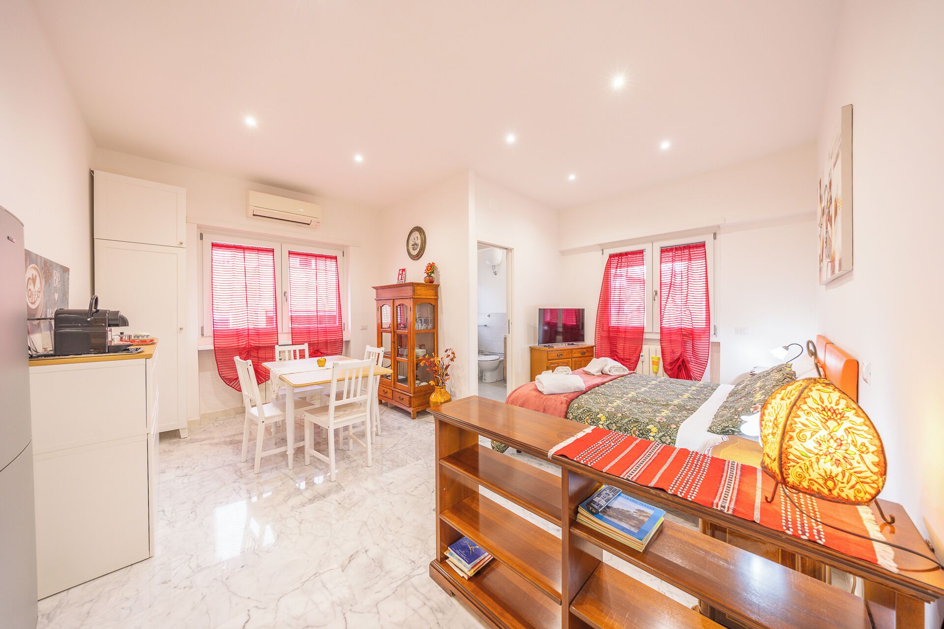 A compact living space with a dining area, a sofa, a TV, and a kitchen area.