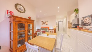 A modern kitchen with white cabinets, a wooden dining table, and a coffee-themed wall art. - Cozy Flat near Vatican and Metro Station (Roma)