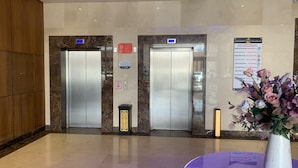 Un vestíbulo moderno con dos ascensores, un mostrador de recepción y un jarrón decorativo.