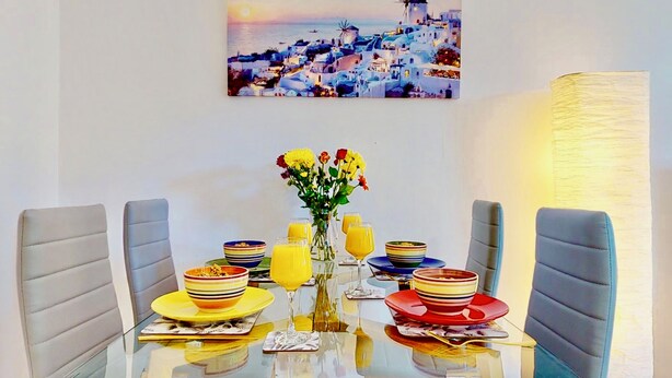 A dining table with striped bowls, glasses, and a vase of flowers.