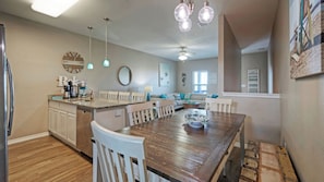 A kitchen with a dining area, wooden flooring, and pendant lighting.
