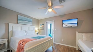 A bedroom with a large bed, a ceiling fan, a television, and a door leading to a balcony. - The Beautiful Place by Avantstay Mins to Beach + Family-friendly Pool (Corpus Christi)