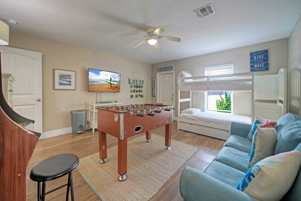 A room with a foosball table, bunk beds, a sofa, and a television. - The Beautiful Place by Avantstay Mins to Beach + Family-friendly Pool (Corpus Christi)