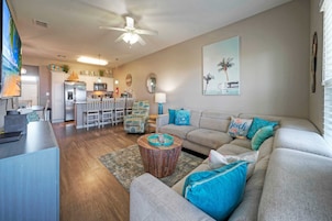 A living room with a sofa, coffee table, and a kitchen in the background.